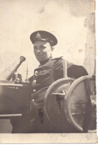 Фотография моряка-офицера на капитанском мостике рядом с морским телеграфом.